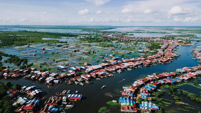 Aerial view of a vibrant floating village with colorful rooftops spread across a flooded lake in Cambodia.